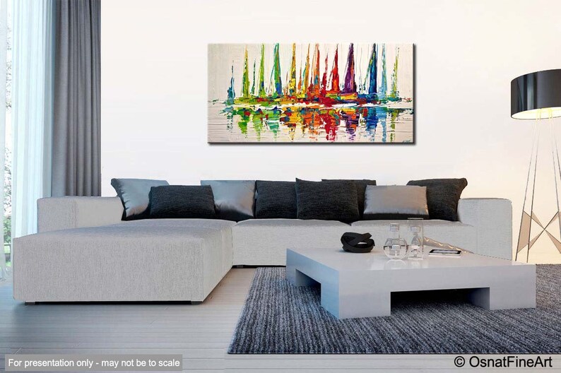 May include: Abstract painting of colorful sailboats on a white background. The sailboats are reflected in the water below. The painting is displayed on a wall in a living room setting.