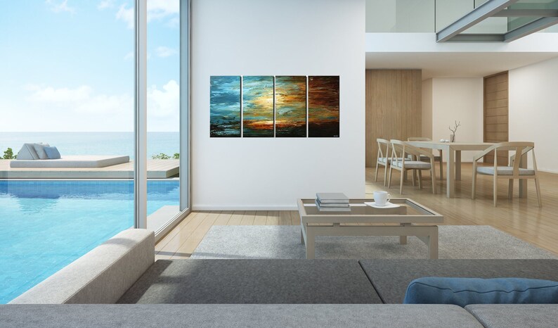 May include: A modern living room with a large window overlooking a pool and ocean. A multi-panel abstract painting depicting a sunset over water hangs on the wall. The painting is in shades of blue, orange, and brown. A coffee table with books and a cup sits in front of the painting.