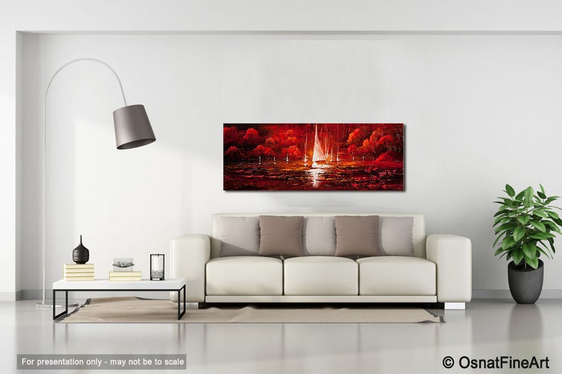 May include: A panoramic oil painting depicts sailboats on a body of water under a red sky. The artwork, with its vibrant red and white hues, is displayed above a white sofa in a modern living room setting. The painting is a landscape with a dramatic, fiery atmosphere.
