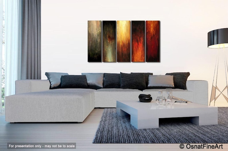 May include: Abstract art piece composed of five vertical panels. Each panel features a blend of colors, including shades of brown, gold, red, and black, creating a textured, flowing effect. The artwork is displayed above a modern white sectional sofa.