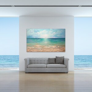May include: A painting of a seascape with a blue sky, white clouds, and a turquoise ocean. The painting is hanging on a white wall in a room with large windows overlooking the ocean.
