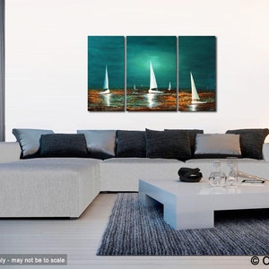 May include: A three-piece abstract painting depicting sailboats on a teal blue body of water with a golden sunset reflection. The painting is displayed on a white wall above a gray sectional sofa with black throw pillows.