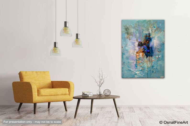May include: Abstract painting with blue, white, and gold hues. The painting is textured and has a modern style. It is hanging on a white wall in a living room setting.