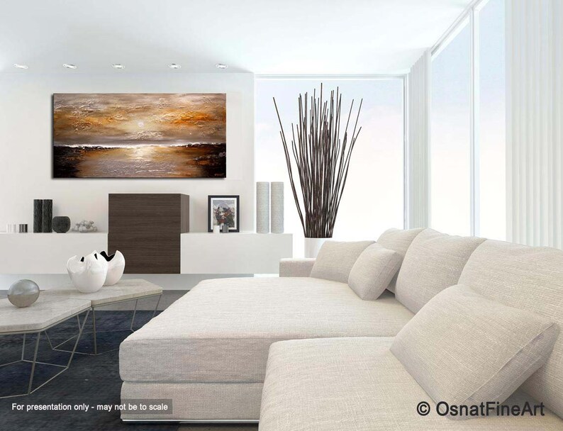 May include: Abstract painting of a sunset over a body of water. The painting is in shades of brown, gold, and white. It is displayed on a white wall in a modern living room setting.