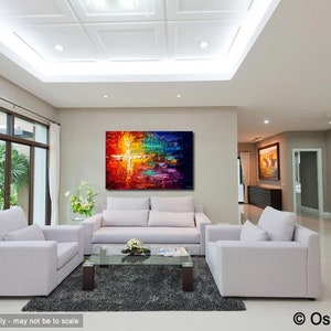 May include: Abstract painting with a cross shape in the center, featuring vibrant colors like red, orange, yellow, green, blue, and purple. The painting is displayed on a wall in a living room setting with white furniture.