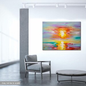 May include: Abstract painting of a colorful sunset over water. The painting is done in a palette of pink, orange, yellow, and blue. The painting is displayed on a white wall in a modern interior.