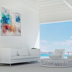 May include: White living room furniture with a white wicker coffee table and two white chairs. The room has a large window with a view of the ocean and sky.