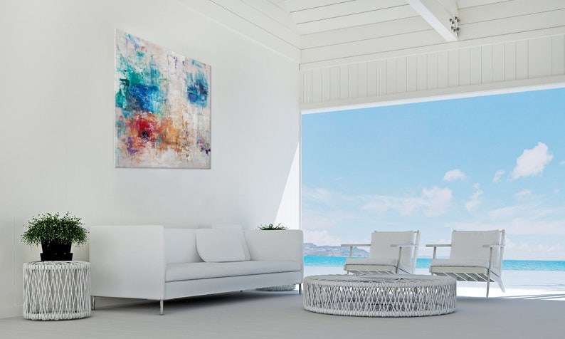 May include: White living room furniture with a white wicker coffee table and two white chairs. The room has a large window with a view of the ocean and sky.
