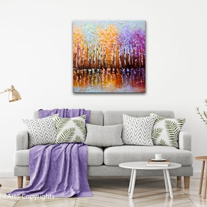 May include: Abstract painting of a forest scene with colorful trees reflected in a still body of water. The trees are painted in shades of orange, yellow, purple, and white. The water is a deep blue with hints of orange and yellow.