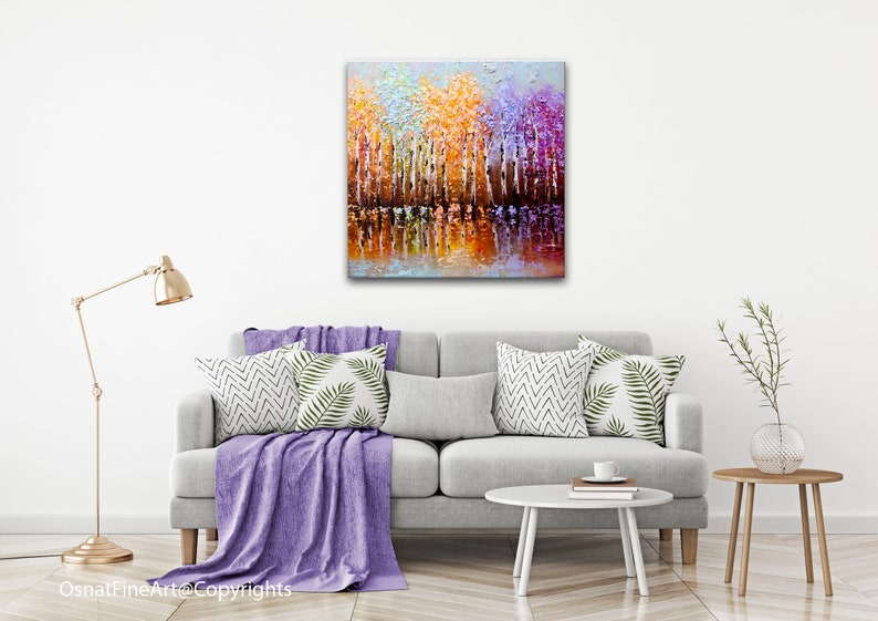 May include: Abstract painting of a forest scene with colorful trees reflected in a still body of water. The trees are painted in shades of orange, yellow, purple, and white. The water is a deep blue with hints of orange and yellow.