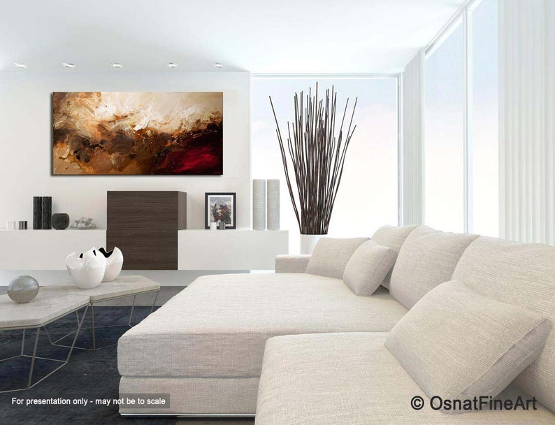 May include: Abstract painting with brown, beige, and red colors. The painting is hanging on a white wall in a modern living room with a white couch and a coffee table.