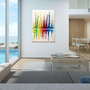 May include: Abstract painting of colorful sailboats reflected in the water. The painting is framed and hanging on a white wall in a modern living room.