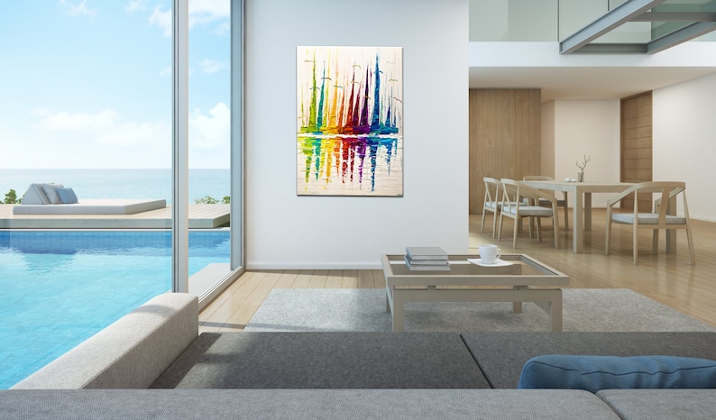 May include: Abstract painting of colorful sailboats reflected in the water. The painting is framed and hanging on a white wall in a modern living room.