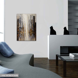 May include: Abstract painting of a city skyline in shades of gray, brown, and gold. The painting is displayed on a white wall in a modern living room setting.