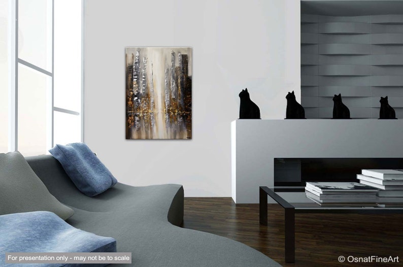 May include: Abstract painting of a city skyline in shades of gray, brown, and gold. The painting is displayed on a white wall in a modern living room setting.