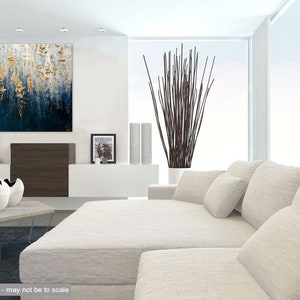 May include: Modern living room with a large abstract painting in shades of blue and gold. A white sectional sofa with several pillows is in the foreground. Decorative vases and a tall plant add to the contemporary design.