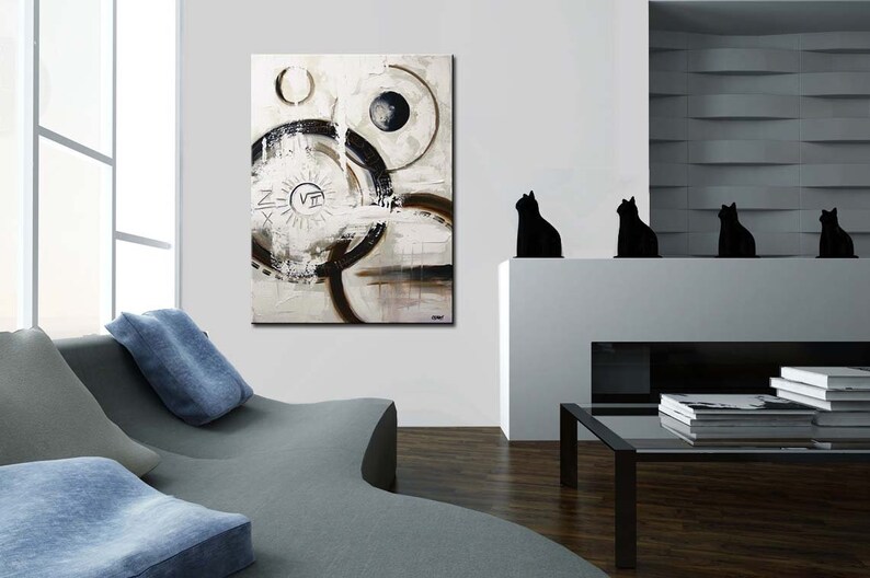 May include: Abstract painting with black and white circles and lines on a white background. The painting is framed and hanging on a white wall in a modern living room.