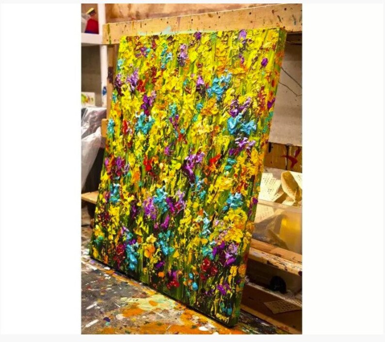 May include: A colorful abstract painting of a field of flowers in shades of yellow, green, blue, purple, and red. The paint is applied in thick, textured strokes, giving the painting a three-dimensional effect.