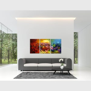 May include: A three-piece abstract art print set featuring a colorful floral design with shades of red, orange, yellow, blue, and purple. The prints are displayed on a white wall above a gray sofa in a modern living room.