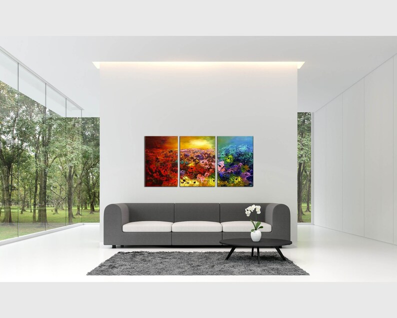 May include: A three-piece abstract art print set featuring a colorful floral design with shades of red, orange, yellow, blue, and purple. The prints are displayed on a white wall above a gray sofa in a modern living room.