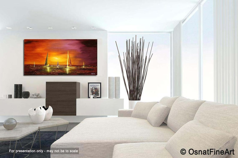 May include: A painting of a sunset over the ocean with sailboats in the distance. The painting is in a modern living room setting with a white couch and a vase of branches.