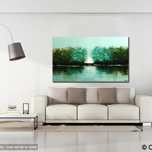 May include: A painting of a lake scene with trees on either side of the water. The trees are a mix of green and blue hues, and the water is a light blue with reflections of the trees. The painting is framed and hanging on a white wall in a living room setting.