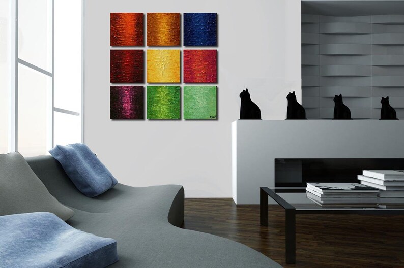 May include: A nine-piece abstract painting set with colorful squares in shades of red, orange, yellow, green, blue, and purple. The paintings are arranged in a grid pattern on a white wall.