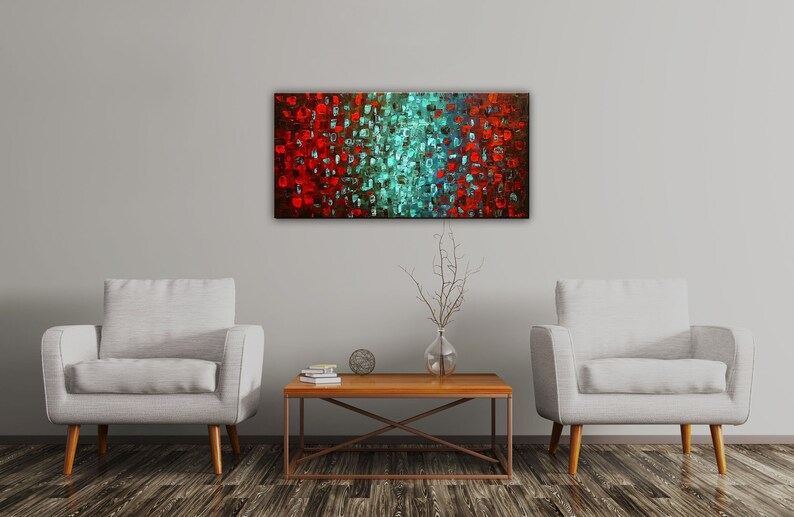 May include: Abstract painting with a red and teal color scheme. The painting is made up of small squares of color, creating a textured effect. The painting is hanging on a white wall in a living room setting.