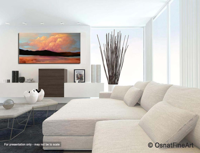 May include: Abstract landscape painting with a pink and orange sky, a dark mountain range, and a reflective body of water. The painting is displayed in a modern living room setting with a white couch and a plant.