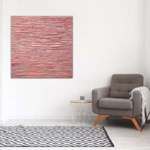 May include: A pink abstract painting with horizontal brushstrokes. The painting is hanging on a white wall in a living room setting.