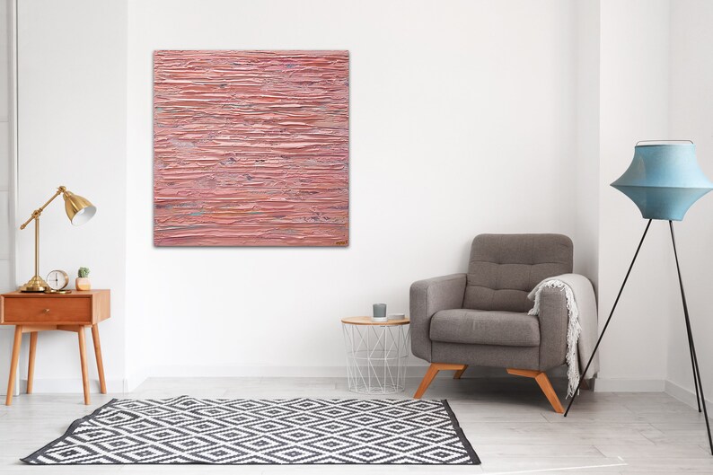 May include: A pink abstract painting with horizontal brushstrokes. The painting is hanging on a white wall in a living room setting.