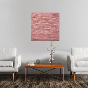 May include: Two white armchairs with wooden legs and a brown wooden coffee table with a metal frame. A pink abstract painting hangs on the wall behind the furniture.