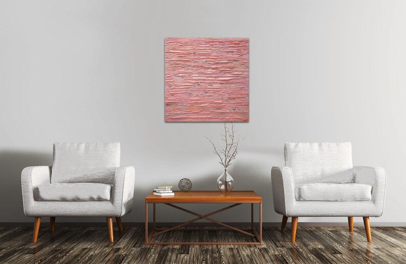 May include: Two white armchairs with wooden legs and a brown wooden coffee table with a metal frame. A pink abstract painting hangs on the wall behind the furniture.