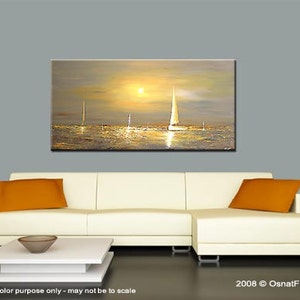 May include: A painting of a seascape with sailboats in the distance, a setting sun, and a golden sky. The painting is displayed on a white couch with orange throw pillows.
