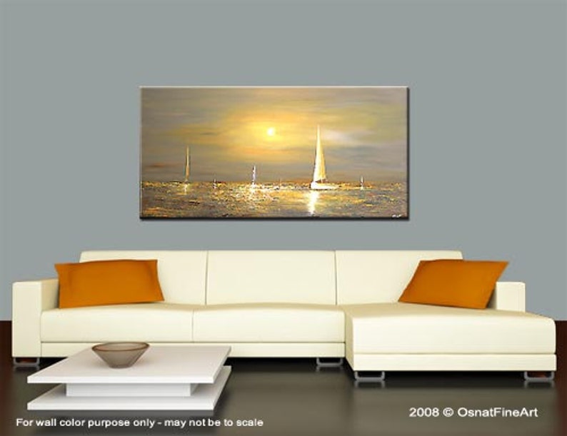 May include: A painting of a seascape with sailboats in the distance, a setting sun, and a golden sky. The painting is displayed on a white couch with orange throw pillows.