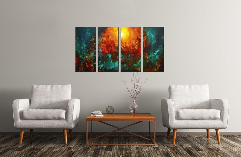 May include: Abstract art painting in four panels, featuring a fiery orange and yellow center surrounded by teal and blue hues. The painting is displayed on a wall above two white armchairs and a wooden coffee table.