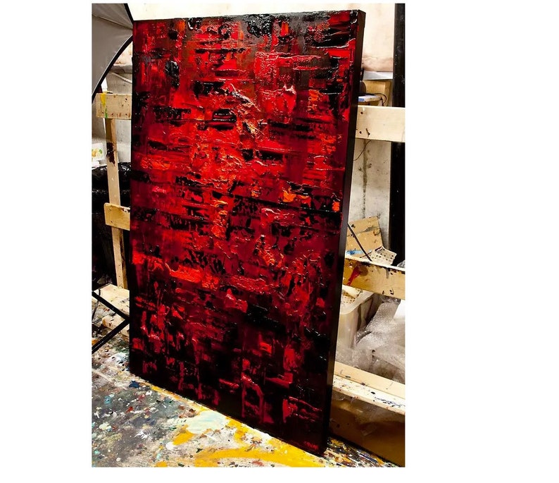 May include: Abstract painting with a textured surface. The painting is dominated by shades of red and black, with hints of orange and yellow. The paint is applied in thick layers, creating a sense of depth and movement.