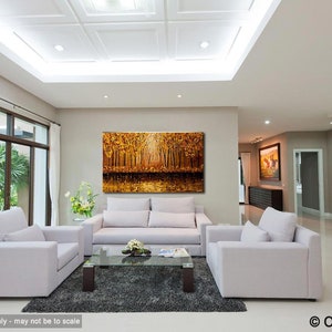 May include: A large abstract painting of a forest scene with golden and brown hues. The painting is hanging on a wall in a living room with white furniture and a glass coffee table.