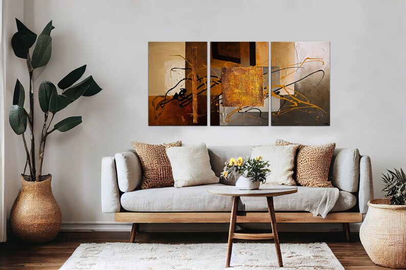 May include: A three-piece abstract art print set with brown, gold, and gray colors. The artwork features geometric shapes and lines, creating a modern and stylish design.