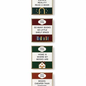 May include: Four square enamel pins with gold-toned edges. Each pin features the text BOOK LOVER in a white cloud shape. The designs include phrases: ESCAPE REALITY READ A BOOK, SO MANY BOOKS SO LITTLE SHELF SPACE, HOME IS WHERE MY BOOKS ARE, and BOOKS: CHEAPER THAN THERAPY.