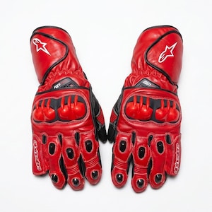 Könnte beinhalten: Paar rote und schwarze Motorradhandschuhe. Die Handschuhe haben eine rote Lederaußenseite mit schwarzen Akzenten und Schutzelementen. Weißes Sternlogo am Bündchen. Die Handschuhe sind auf Schutz und Leistung ausgelegt.