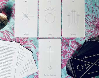 Può includere: Un set di carte dei tarocchi con illustrazioni in bianco e nero su cartoncino bianco. Le carte sono disposte su una tovaglia da tavolo floreale blu e rosa. Le carte includono La Stella, il Re di Denari, l'Otto di Spade e La Sacerdotessa.