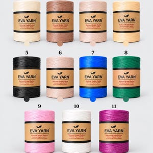 Könnte beinhalten: Elf zylindrische Spulen aus natürlichem Papierbast von Eva Yarn in verschiedenen Farben, jede mit einem braunen Band versehen, das den Markennamen und Text trägt. Die Farben umfassen Creme, Braun, Beige, Gelb, Schwarz, Hellrosa, Blau, Grün, Pink, Weiß und Magenta.