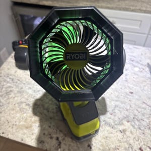 May include: A portable Ryobi fan featuring a black octagonal frame surrounding a lime green and black fan blade assembly. The center of the fan displays the Ryobi brand name in white text on a dark background, with a lime green base unit.