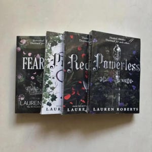 Pode incluir: S&atilde;o exibidos quatro livros de capa dura com capas escuras. Os t&iacute;tulos incluem "Fear", "Powerless" e "Red". Os livros apresentam desenhos florais e decorativos. O nome do autor, Lauren Roberts, &eacute; vis&iacute;vel nas capas.