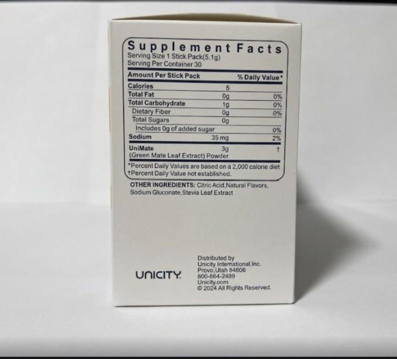 K&ouml;nnte beinhalten: Eine wei&szlig;e Schachtel mit dem Text "Supplement Facts" und N&auml;hrwertangaben. Die Schachtel listet Kalorien, Gesamtfett, Kohlenhydrate, Ballaststoffe, Zucker und Natriumgehalt auf. Der Markenname "Unicity" ist unten links aufgedruckt.
