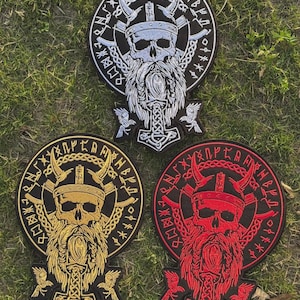 Könnte beinhalten: Drei gestickte Aufnäher mit einem Wikinger-Schädel mit gehörntem Helm, Bart und dem Symbol von Thors Hammer. Die Aufnäher sind in Schwarz, Gold und Rot gehalten, mit weißen, goldenen und roten Details. Jeder Aufnäher hat ein rundes Design mit Runen.