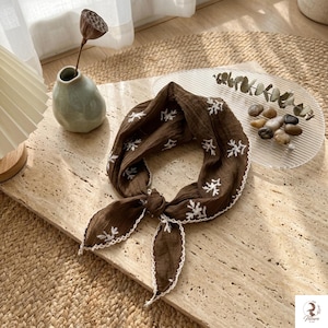 Soft fabric triangle scarf folded and displayed with natural decor