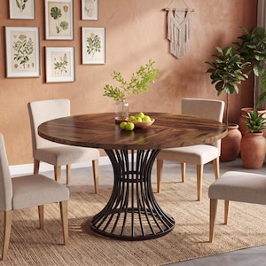 May include: A round wooden dining table with a dark brown herringbone pattern top and a black metal pedestal base, surrounded by four beige upholstered chairs with light wood legs, arranged on a woven rectangular area rug.