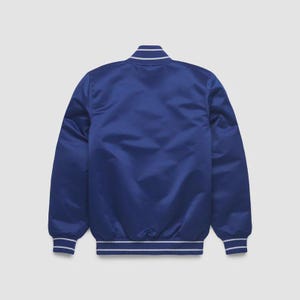 May include: A royal blue satin bomber jacket with white striped trim on the collar, cuffs, and hem. The back of the jacket is smooth and unadorned, with a slight sheen. The jacket is a classic style.
